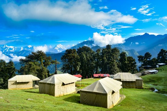 Chopta meadows with tented camps and Himalayan peaks in the distance